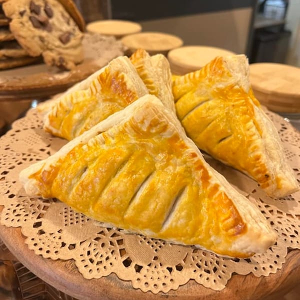 Three golden-brown pastries with flaky crusts and decorative slits, served on a doily at Morning Talk Cafe.