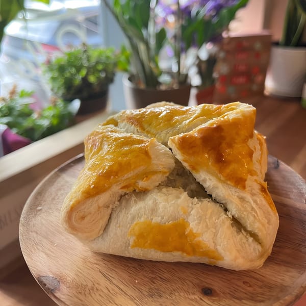 Golden-brown pastry with a flaky crust, served on a wooden plate at Morning Talk Cafe.